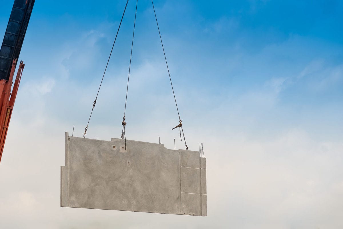 Construction site crane is lifting a precast concrete wall panel